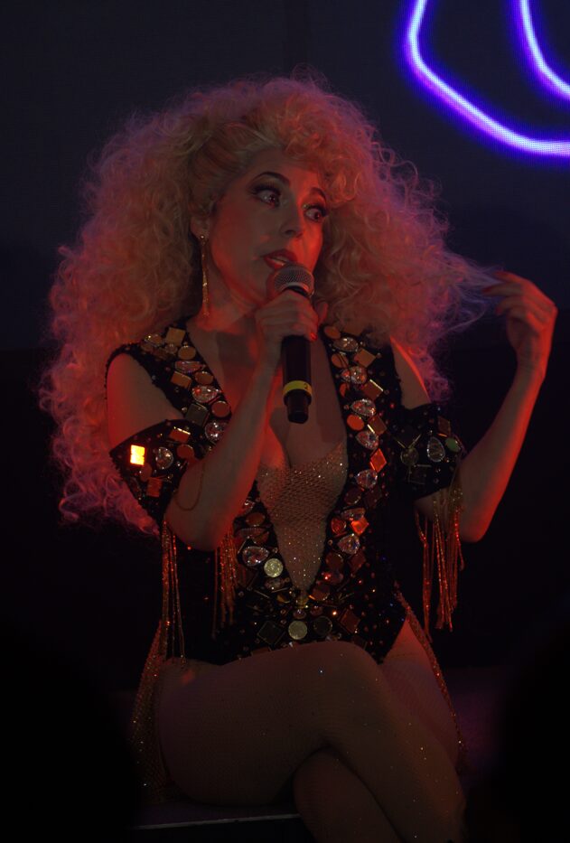 Cantante del Show Despecho con peluca rizada y micrófono